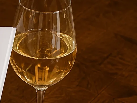 Glas witte wijn op een houten tafel bij Wijnbar 1852, met de rand van de wijnkaart in beeld
